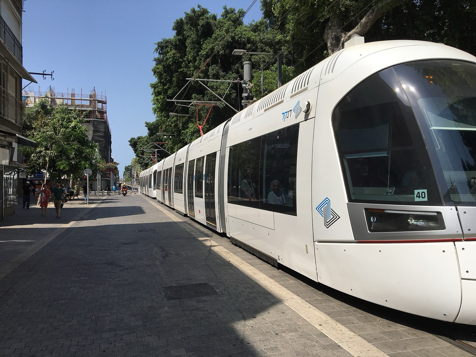 A Red Line light rail tram on a tree-lined Tel Aviv street