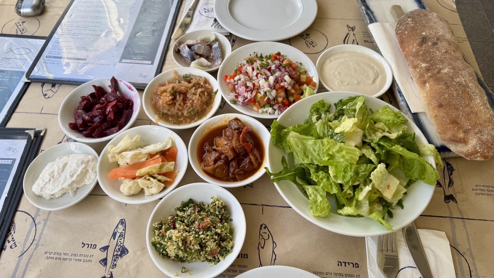 A table covered in small Israeli salads, the bottomless salatim that arrive before a meal