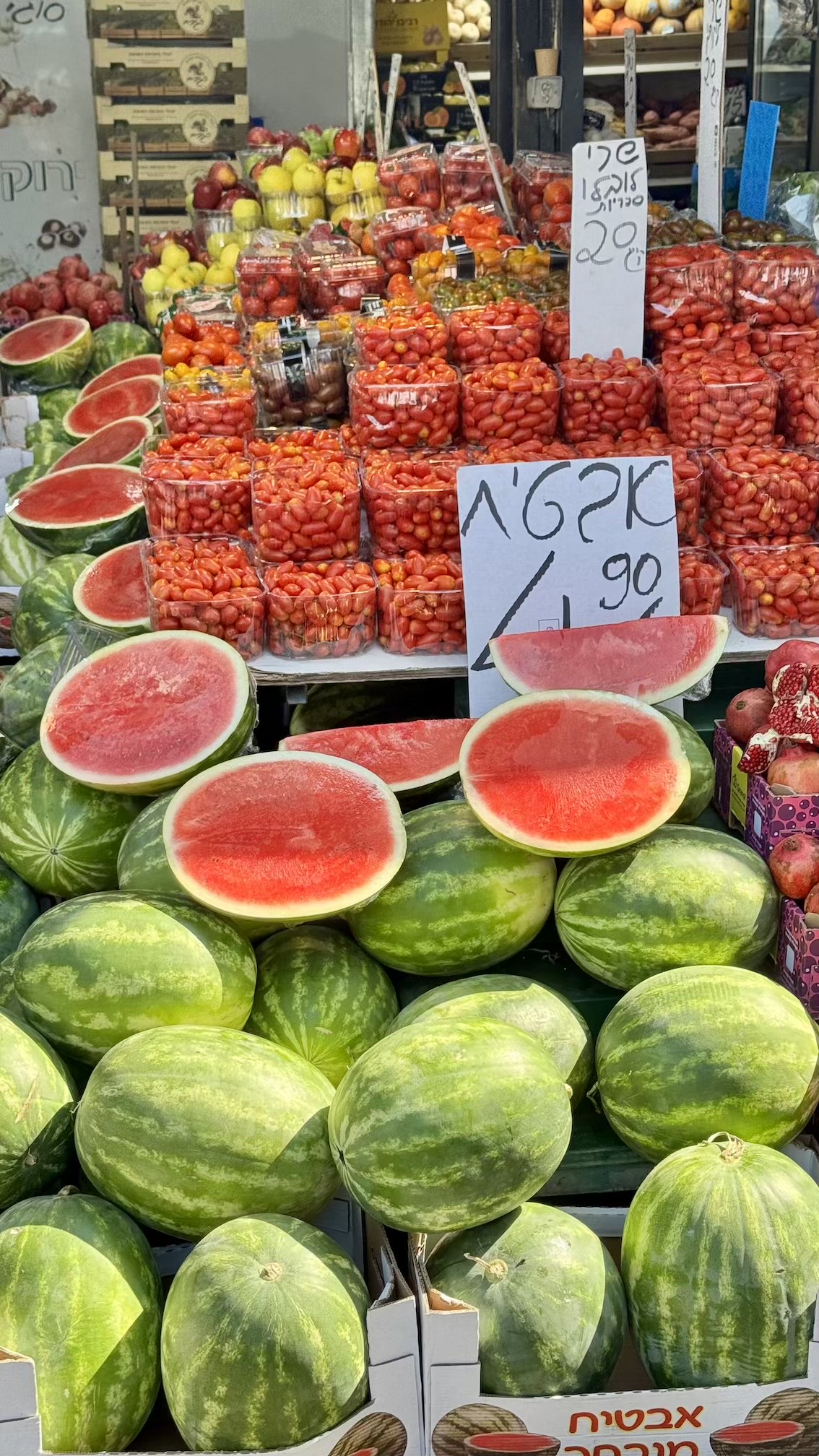 Watermelons, tomatoes and pomegranates on a stall at Carmel Market